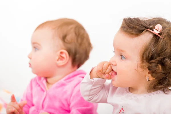 Photo of two adorable baby sitting on the bed and nibbles — Stock Photo, Image