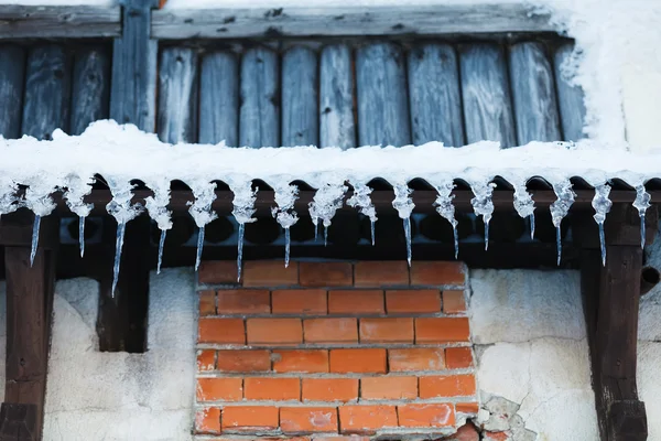 Ijspegels op een houten muur — Stockfoto