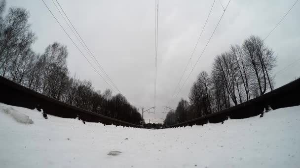 Telecamera estrema è montato sotto il treno sulle rotaie. Il treno suburbano passa sopra la telecamera. inverno tiro — Video Stock