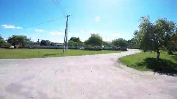 Videocámara entre las ruedas del coche. La cámara vuela sobre la carretera. La cámara flota al margen. Aldea a lo largo de bordillo — Vídeos de Stock