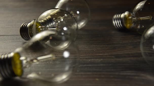 茶色の木製の背景に光る電球。多くのランプと 1 つだけ点灯。コンセプトのアイデア — ストック動画
