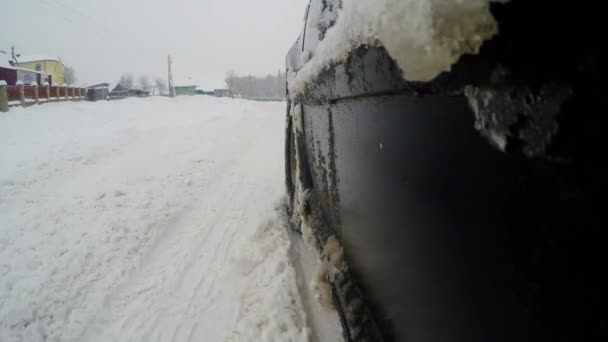 Primer plano de la rueda en carreteras nevadas. El coche pasea por las calles nevadas de la ciudad — Vídeo de stock