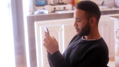  Şok olmuş genç bir adam cep telefonundan kötü haberler okuyor.