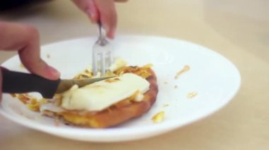 Genç adam zorlukla bir dilim pizza yiyor.