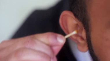 Kirli kulakları pamuklu bezlerle temizleyen adam.