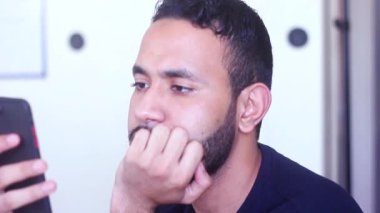 Sosyal medyayı kontrol etmek için akıllı telefonunu kullanan sıkılmış bir adam.