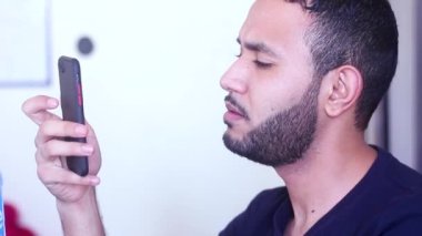 Akıllı telefonunu kullanan bir adam kameraya bakıp gülümsüyor.