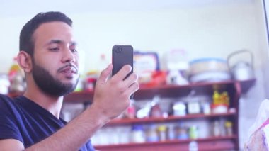 Ketchen 'de oturan genç adam bir mesaj ya da e-posta alıyor.