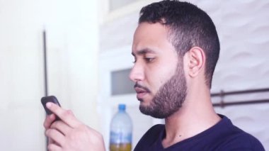 Neşeli ve neşeli sakallı adam elinde bir cep telefonu ve gülümsüyor.