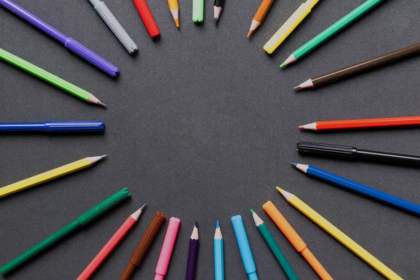 A rainbow of colored pencils, on a dark background.