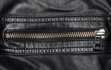 Siyah desenli metal fermuarlı deri. Siyah deri arka planda metal fermuar. Fermuarlı siyah deri ceketin yakın çekimi..