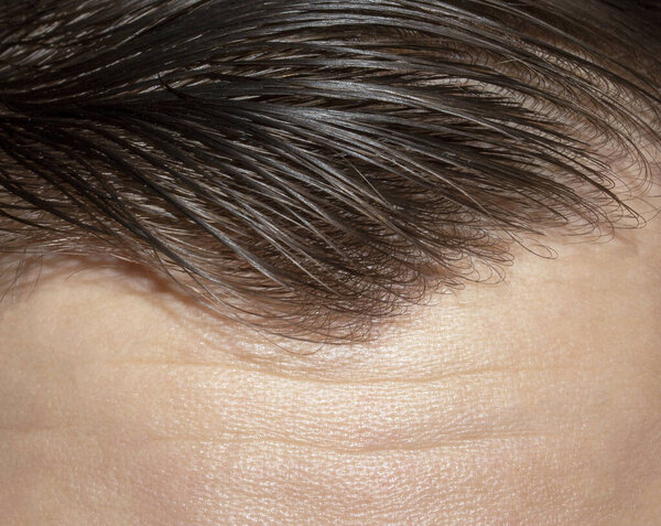 A man's forehead is furrowed.Wrinkles on the forehead background photo.The forehead is lined and creased.