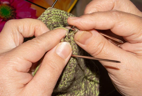 A woman knits wool socks with knitting needles.Women\'s hands knit knitting needles background.