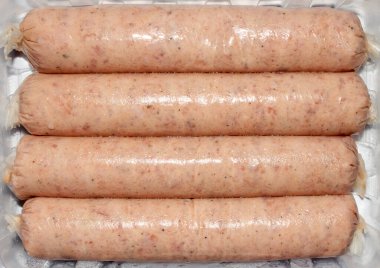 Tavuk sosisleri yarı pişmiş et dilimlenmiş. Arka planda tavuk sosisi var..