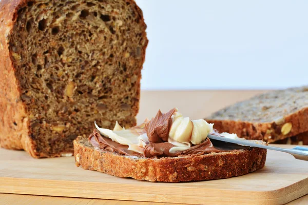 Chocolade en vanille, romige verspreid over sneetje bruin hele tarwe brood — Stockfoto