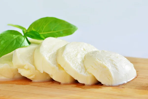 Mozzarella kaas en basilicum op een houten bord — Stockfoto
