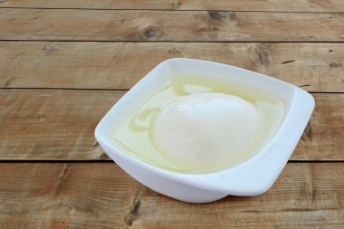 Ahşap masa üzerinde bir porselen tabak salamura sırılsıklam mozzarella peyniri