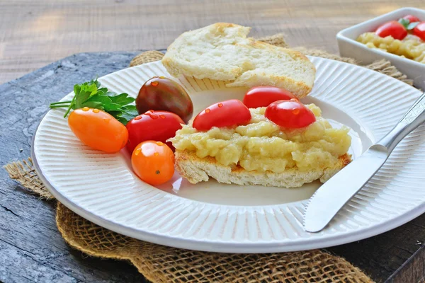 Purê de berinjela assada espalhado em pão torrado com tomate cereja — Fotografia de Stock