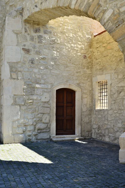 Pared de piedra con puerta y ventana de madera. Luz proveniente de un tragaluz (oculus) detrás del arco . — Foto de Stock