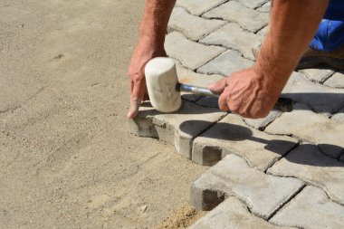 Worker laying interlocking concrete pavers clipart