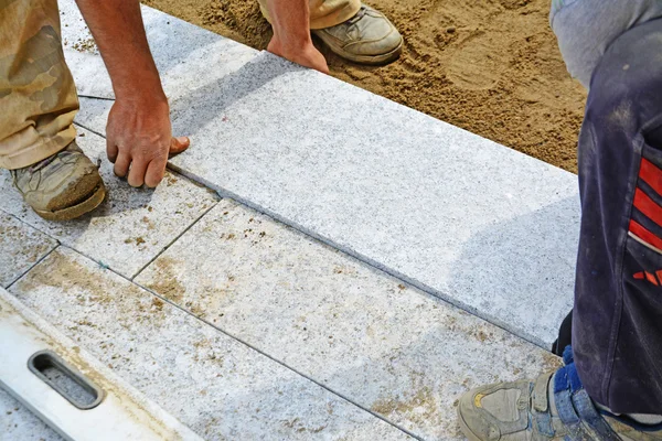 Workers laying granite block paver in place — Stock Photo, Image