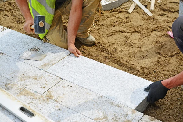 Arbetaren knacka paver på plats med gummiklubba. — Stockfoto