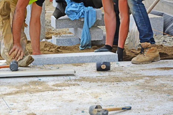 Travailleurs pose paveuse bloc de granit en place . Images De Stock Libres De Droits