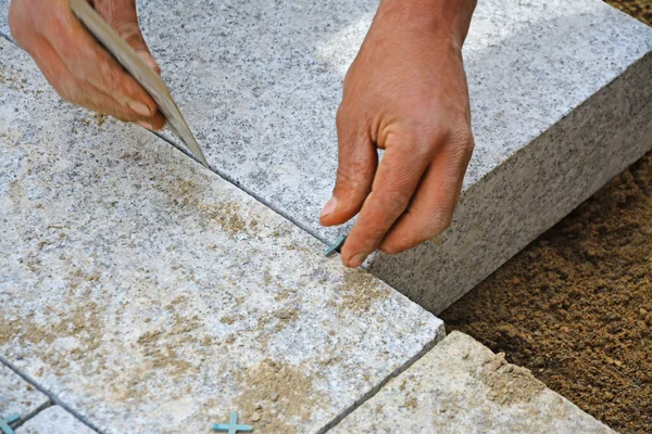 Travailleur crée un assemblage étroit entre les blocs de pavage Photo De Stock