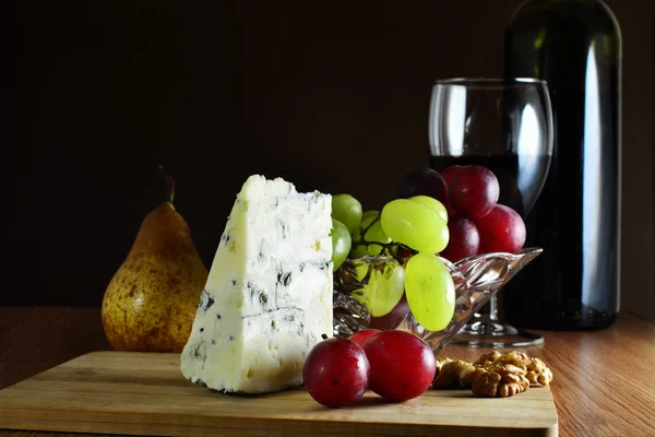 Cunha de queijo francês de veios azuis com uvas e vinho tinto . — Fotografia de Stock