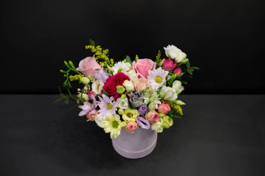 Dekoratif ambalajda koyu renk bir çiçek buketi..