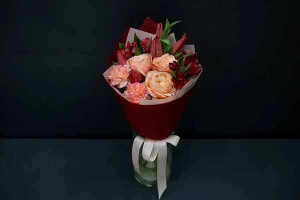 A bouquet of flowers in decorative packaging on a dark background.