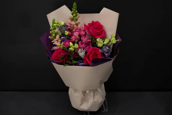 A bouquet of flowers in decorative packaging on a dark background.