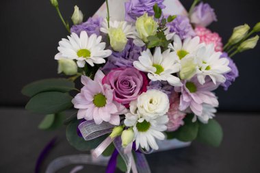 Taze çiçekler bir bukette toplanır. Leylak renginde çiçeklerle dolu bir şapka kutusu.