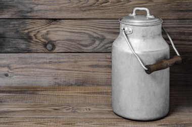 Yatay biçimde ahşap arka plan üzerinde eski süt olabilir alüminyum