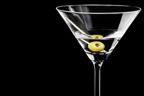 Nahaufnahme von trockenen Martini mit grünen Oliven auf schwarzem Hintergrund — Stockfoto