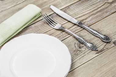 Beyaz bir tabak, çatal, bıçak ve bir ahşap zemin üzerine yeşil peçete yemek odası