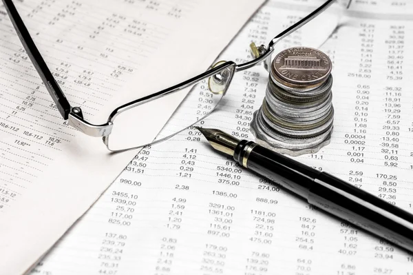 Coins, spectacles and a fountain pen on a data table — Stock Photo, Image