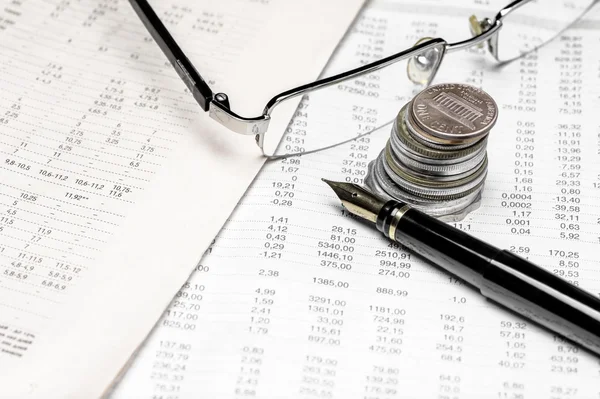 Coins, spectacles and a fountain pen on a data table — Stock Photo, Image