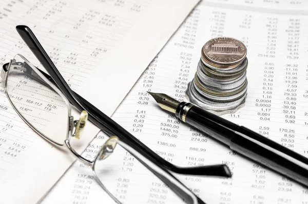 Coins, spectacles and a fountain pen on a data table — Stock Photo, Image