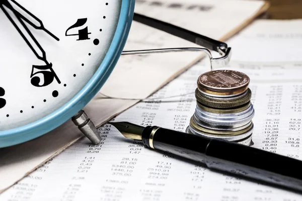 Münzen, Uhr, Brille und Füllfederhalter auf einem Datentisch — Stockfoto