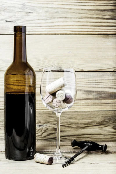 Mantarlar, tirbuşon, bir bardak şarap ve bir şişe ahşap arka plan üzerinde
