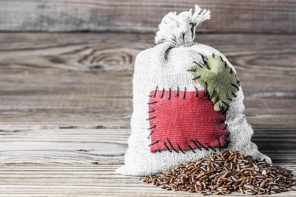 Tasarruf depolama kavramı. Çuvala ahşap arka plan üzerinde yama ile kırmızı pirinç