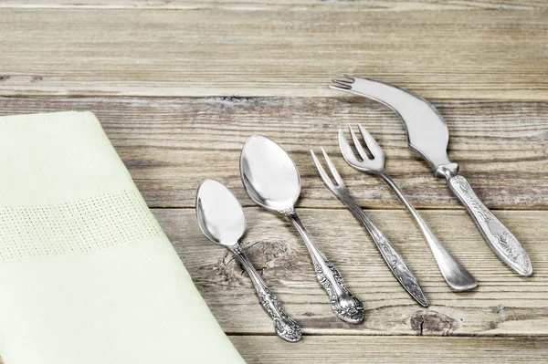 Bir çatal bıçak seti ve bir ahşap zemin üzerine yeşil peçete yemek odası