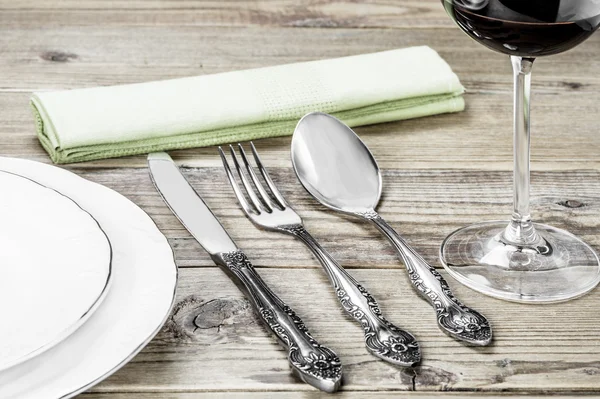 Beyaz bir tabak, çatal, bıçak, bir yeşil peçete yemek odası ve ahşap arka plan üzerinde bir şarap kadehi