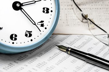 Saat, gözlük ve veri tablosu üzerinde bir dolma kalem