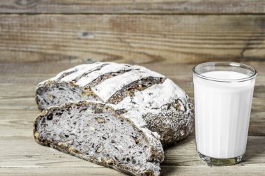 Süt cam ve ahşap arka plan üzerinde biraz ekmek