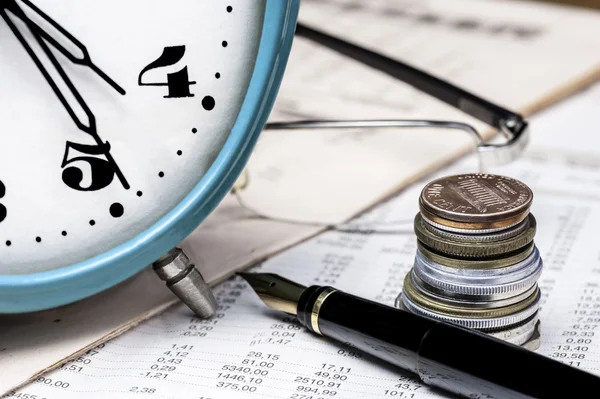 Münzen, Uhr, Brille und Füllfederhalter auf einem Datentisch — Stockfoto