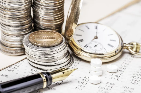 Coins, a clock , a fountain pen and tablets on  a data table — Stock Photo, Image