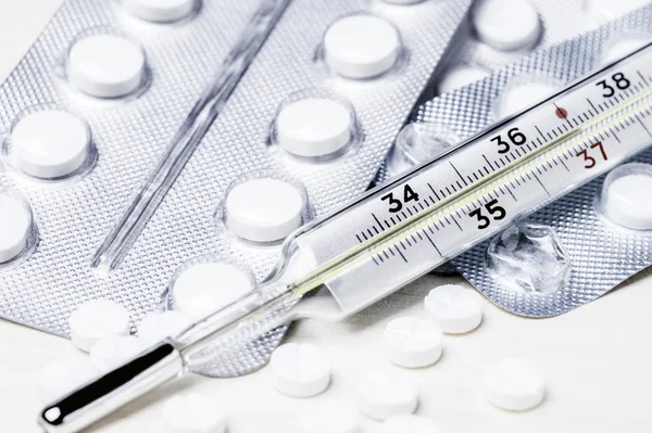 Beyaz tıp tablet blister ve termometre ahşap bir masa üzerinde kapat