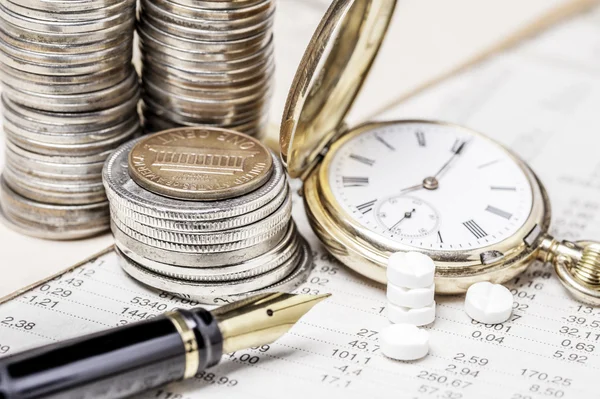 Münzen, eine Uhr, Füllfederhalter und Tablets auf einem Datentisch — Stockfoto